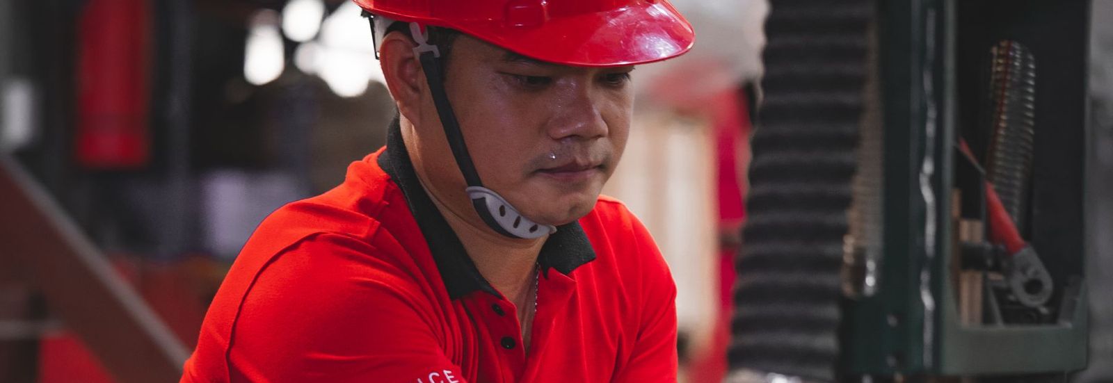 A technician in a red helmet adjusting a machine